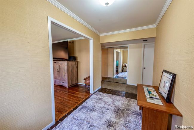 Hall with crown molding and dark wood finished floors | Image 18