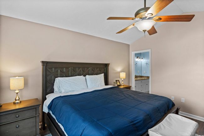 Bedroom featuring vaulted ceiling, wood finished floors, ensuite bath, and ceiling fan | Image 11