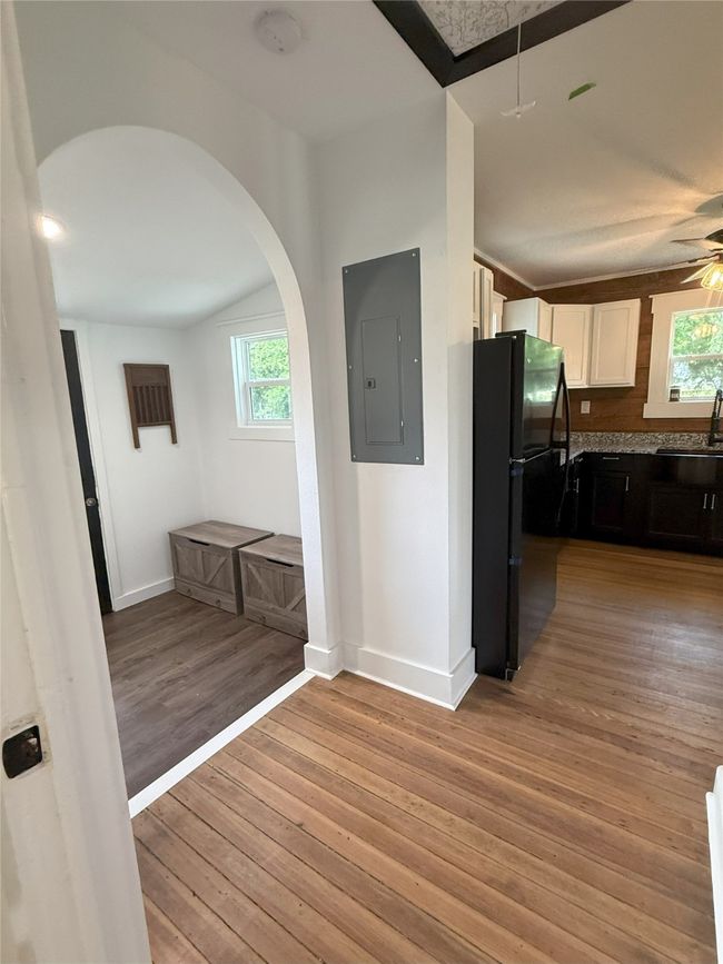 Kitchen with electric panel, freestanding refrigerator, arched walkways, light wood finished floors, and white cabinets | Image 12