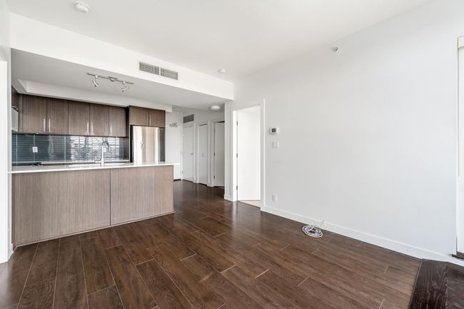 Kitchen featuring freestanding refrigerator, light countertops, dark wood-style flooring, decorative backsplash, and a peninsula | Image 14