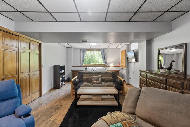 Spacious lower-level amusement room featuring a wet bar, new flooring, and a large window with serene views of the backyard—currently serving as a second living area. | Image 30