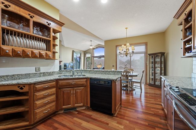 Main level kitchen adjacent to the dining area and primary living space with creative custom storage solutions! You will appreciate the generous granite counter space with the sink facing outward keeping you connected to the living and dining areas. | Image 11
