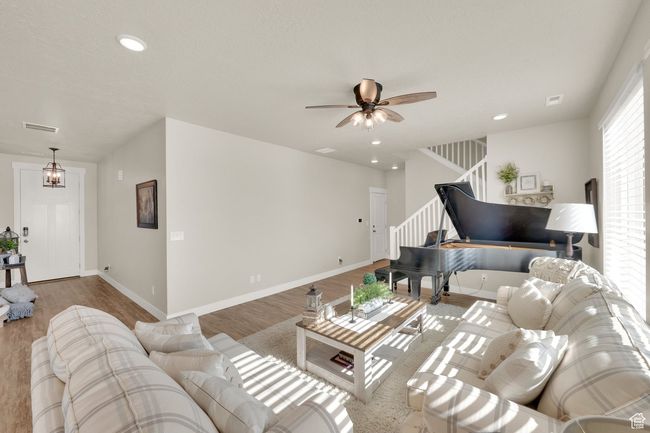 Living room featuring stairs, wood finished floors, a ceiling fan, recessed lighting, and baseboards | Image 5