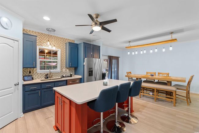 Kitchen featuring stainless steel fridge with ice dispenser, a sink, blue cabinets, ornamental molding, and light wood finished floors | Image 5
