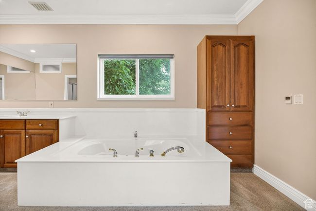 Bathroom with vanity, a jetted tub, crown molding, and baseboards | Image 17