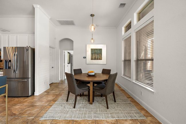 The breakfast area offers a delightful space for casual dining, perfectly positioned to capture abundant natural light through oversized windows. Open to the living room and kitchen, this inviting space features tile flooring and modern lighting, creating a seamless flow for everyday meals and gatherings. | Image 21