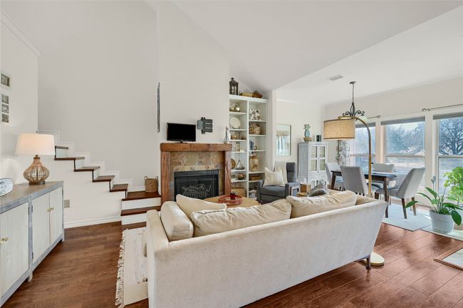Living room featuring dark wood finished floors, high vaulted ceiling, a tiled fireplace, a chandelier, and baseboards | Image 4