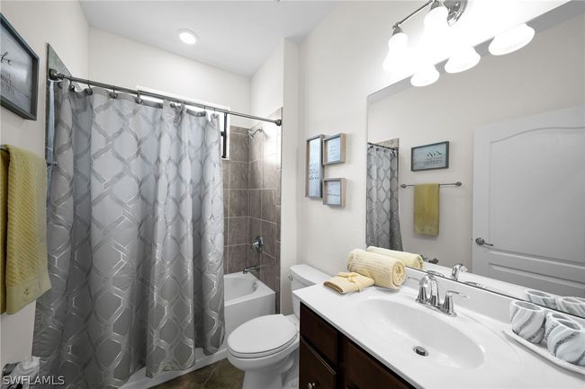 Full bathroom featuring vanity, shower / bathtub combination with curtain, tile patterned flooring, and toilet | Image 22