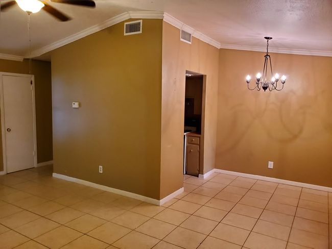 Spare room with a chandelier, a ceiling fan, light tile patterned floors, crown molding, and baseboards | Image 17