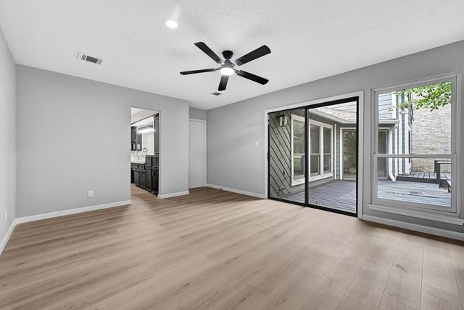 Another angle of the spacious primary bedroom showcasing sliding glass doors that open to a private deck, ample natural light, and a seamless flow into the beautifully updated en-suite bathroom. | Image 26
