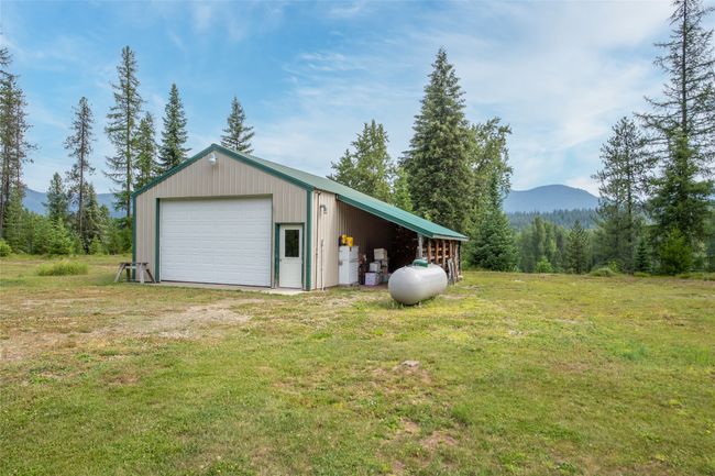 Garage featuring a detached garage, a mountain view, and a view of trees | Image 12