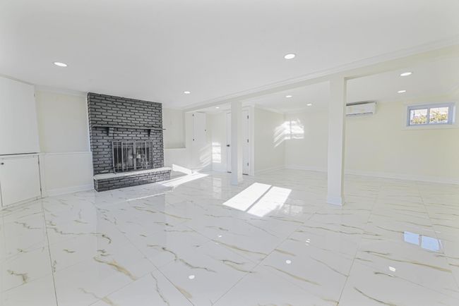Unfurnished living room with a brick fireplace, crown molding, and an AC wall unit | Image 41