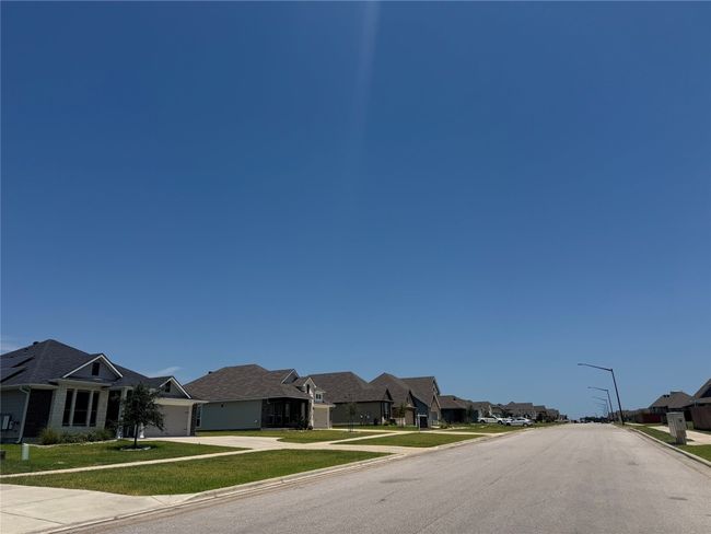 View of asphalt road featuring sidewalks, curbs, street lights, and a residential view | Image 17