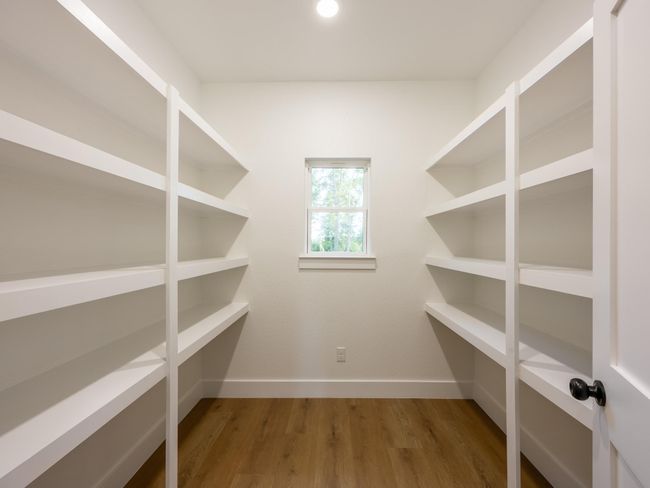 Storage is never an issue with this walk-in pantry featuring built-in shelving and a window for natural light—perfect for keeping your kitchen essentials organized and within reach. | Image 19