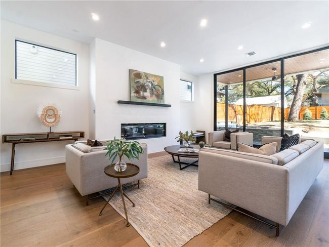 Living room featuring wood finished floors, a glass covered fireplace, and recessed lighting | Image 7