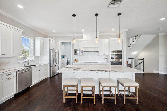 View of kitchen and center island. Pantry/laundry room in back left of photo. | Image 28
