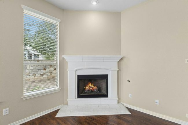 Detailed view of wood finished floors, a lit fireplace, and baseboards | Image 12