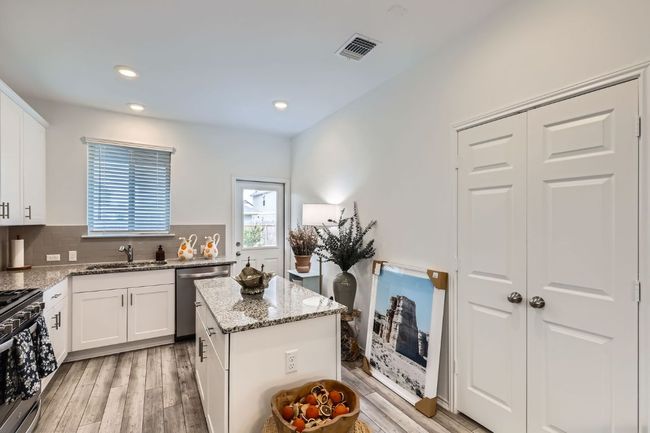Kitchen with stainless steel appliances, a sink, light stone counters, light wood-style floors, and decorative backsplash | Image 9