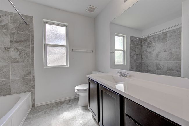 Full bathroom featuring toilet, vanity, baseboards, and shower combination | Image 24