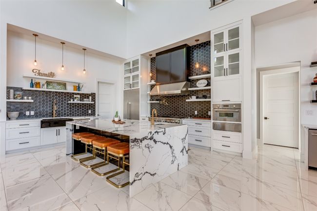 Kitchen featuring open shelves, stainless steel appliances, decorative backsplash, and white cabinetry | Image 10