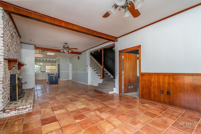 Unfurnished living room with ceiling fan, a fireplace, wood walls, and ornamental molding | Image 6