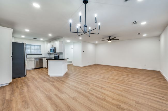 Kitchen featuring white cabinetry, dark countertops, visible vents, appliances with stainless steel finishes, and ceiling fan with notable chandelier | Image 16