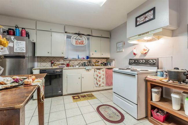 Kitchen featuring dishwasher, backsplash, freestanding refrigerator, and white range with electric stovetop | Image 11