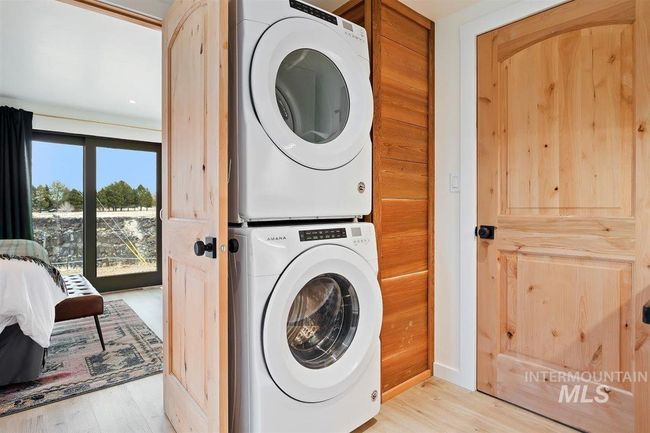 Washroom with stacked washing machine and dryer and light wood-type flooring | Image 27