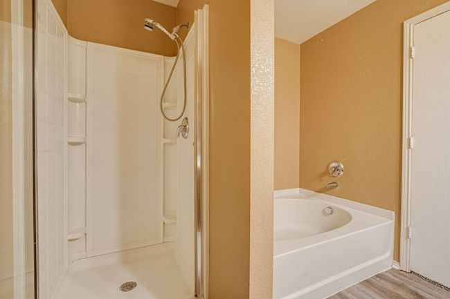 Full bathroom with a stall shower, a bath, a textured wall, and wood finished floors | Image 18