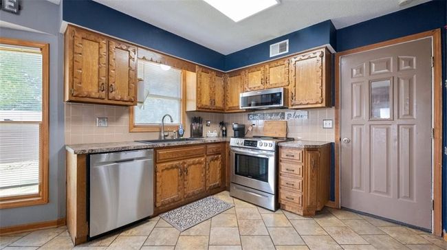 Kitchen featuring appliances with stainless steel finishes, brown cabinets, backsplash, and light countertops | Image 6