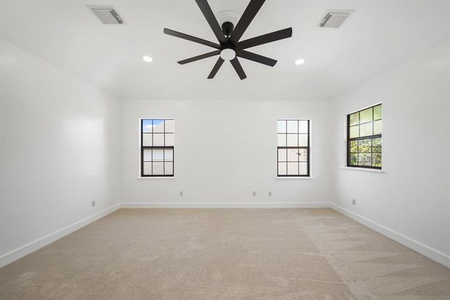 The fourth bedroom with shared access to the fourth full bath includes a high ceiling with recessed lights, ceiling fan with lighting, windows overlooking the side & front yards of the home & new carpet. | Image 37