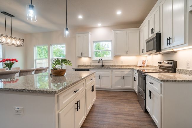 Kitchen featuring stainless steel appliances, healthy amount of natural light, white cabinets, a center island, and recessed lighting | Image 9