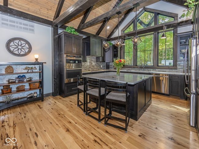 kitchen with stainless steel appliances, decorative backsplash, a sink, light wood-type flooring, and light stone counters | Image 14