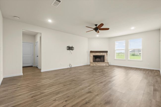 Unfurnished living room featuring a ceiling fan, a brick fireplace, wood finished floors, and recessed lighting | Image 12