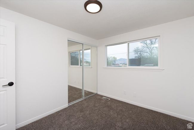 Unfurnished bedroom featuring baseboards, a closet, dark carpet, and visible vents | Image 22