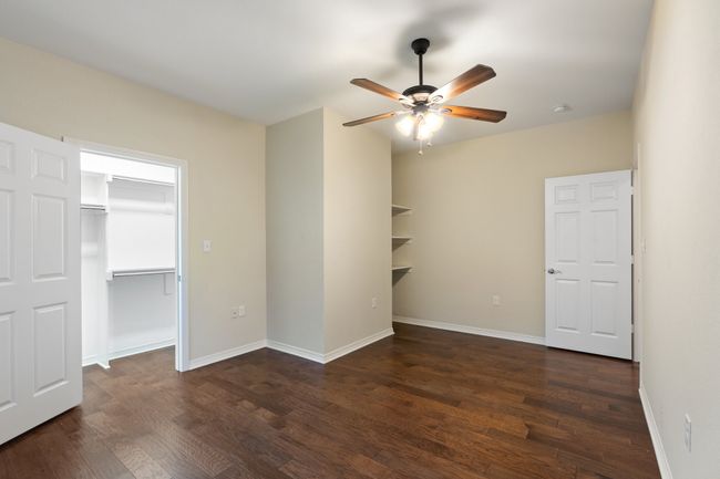 Unfurnished bedroom with dark wood-style flooring, a closet, a spacious closet, and baseboards | Image 10
