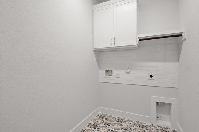 Laundry area featuring hookup for an electric dryer, baseboards, hookup for a washing machine, tile patterned flooring, and cabinet space | Image 24