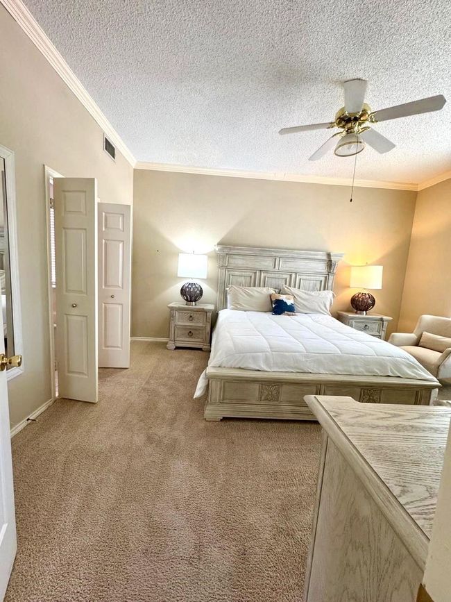 Bedroom with a textured ceiling, light colored carpet, crown molding, and visible vents | Image 11