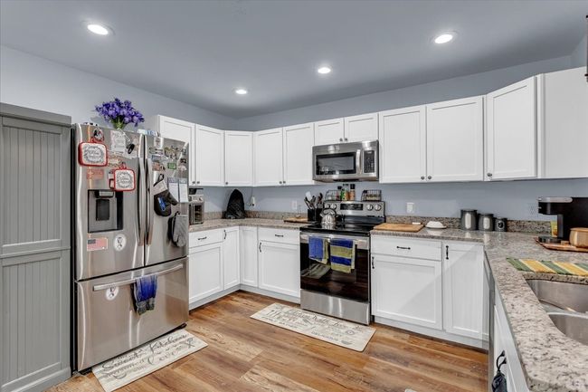 Kitchen featuring appliances with stainless steel finishes, white cabinetry, light wood-style floors, recessed lighting, and light stone counters | Image 9