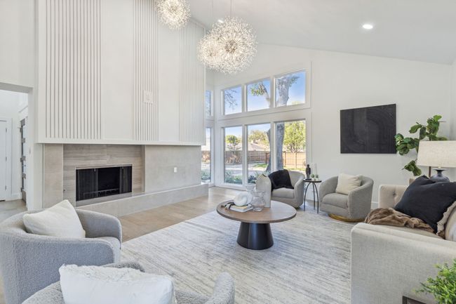 Living room featuring wood finished floors, a premium fireplace, high vaulted ceiling, recessed lighting, and a chandelier | Image 7