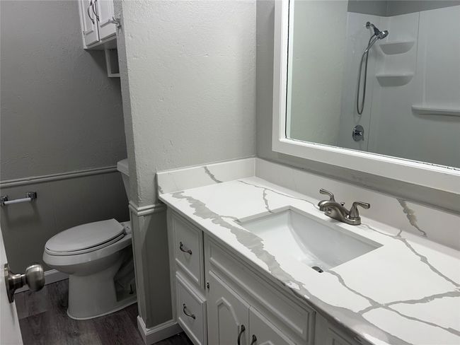 Full bathroom featuring wood finished floors, vanity, a wainscoted wall, a shower, and a textured wall | Image 10