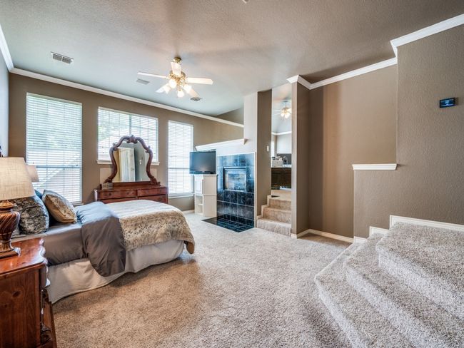 Carpeted bedroom with crown molding, a fireplace, a textured ceiling, and ceiling fan | Image 17
