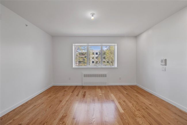 Empty room featuring radiator heating unit, baseboards, and light wood-style floors | Image 29