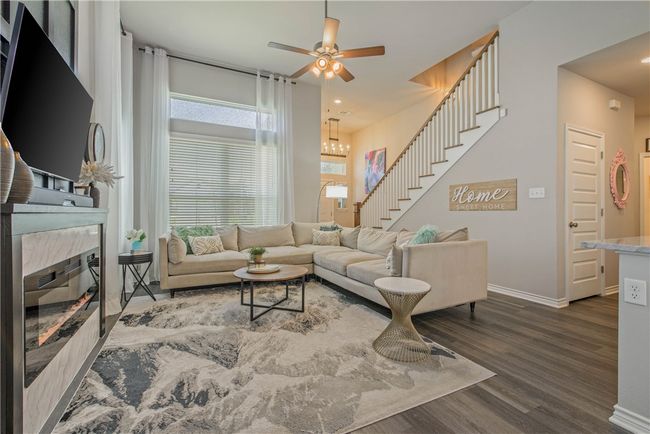 Living room with wood finished floors, stairs, and a ceiling fan | Image 7