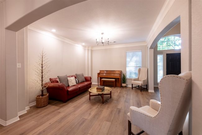 Living room featuring a chandelier, crown molding, light wood-style flooring, arched walkways, and recessed lighting | Image 9