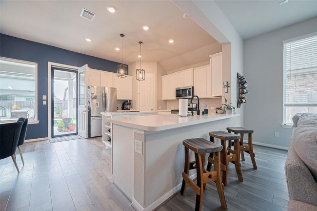 Open kitchen with bar stool seating, island kitchen with shelving and stainless steel appliances. | Image 21
