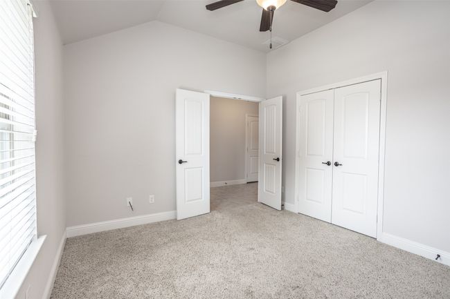 Unfurnished bedroom with carpet floors, lofted ceiling, a closet, and a ceiling fan | Image 5