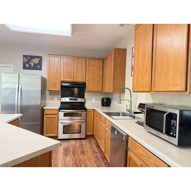 Island kitchen with black and stainless electric range, stainless dishwasher and also has a disposal | Image 19