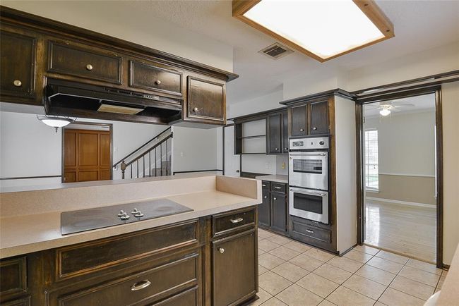 Kitchen features a glass electric cooktop and double ovens. | Image 8
