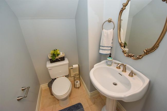 Formal powder room on the first floor featuring a pedestal sink, toilet, and an ornate mirror | Image 28